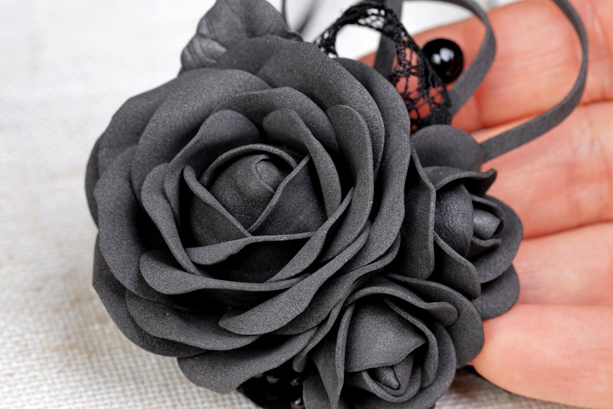 a hand holding a black flower on a white cloth