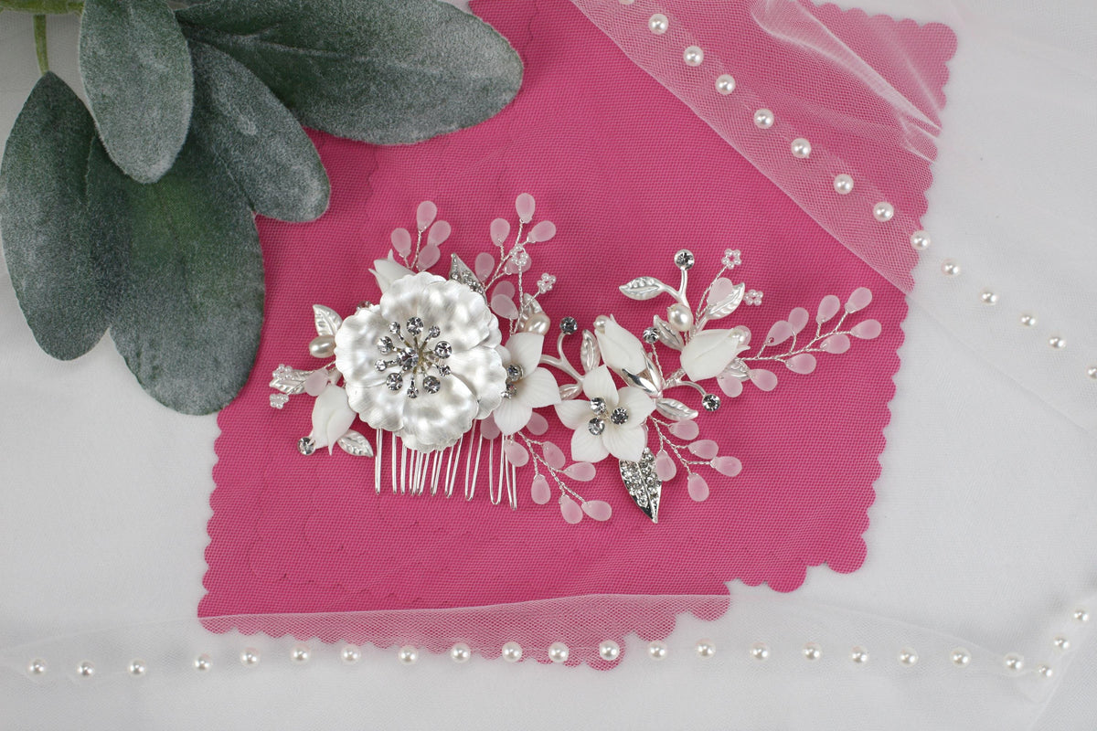a hair comb with flowers and pearls on a pink cloth