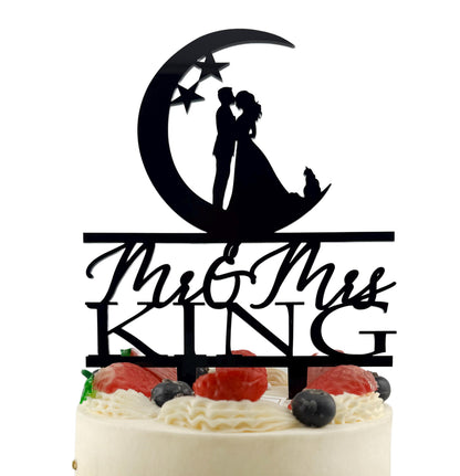A black silhouette of a bride and groom on a crescent moon and stars, with the words "Mr & Mrs" written below.