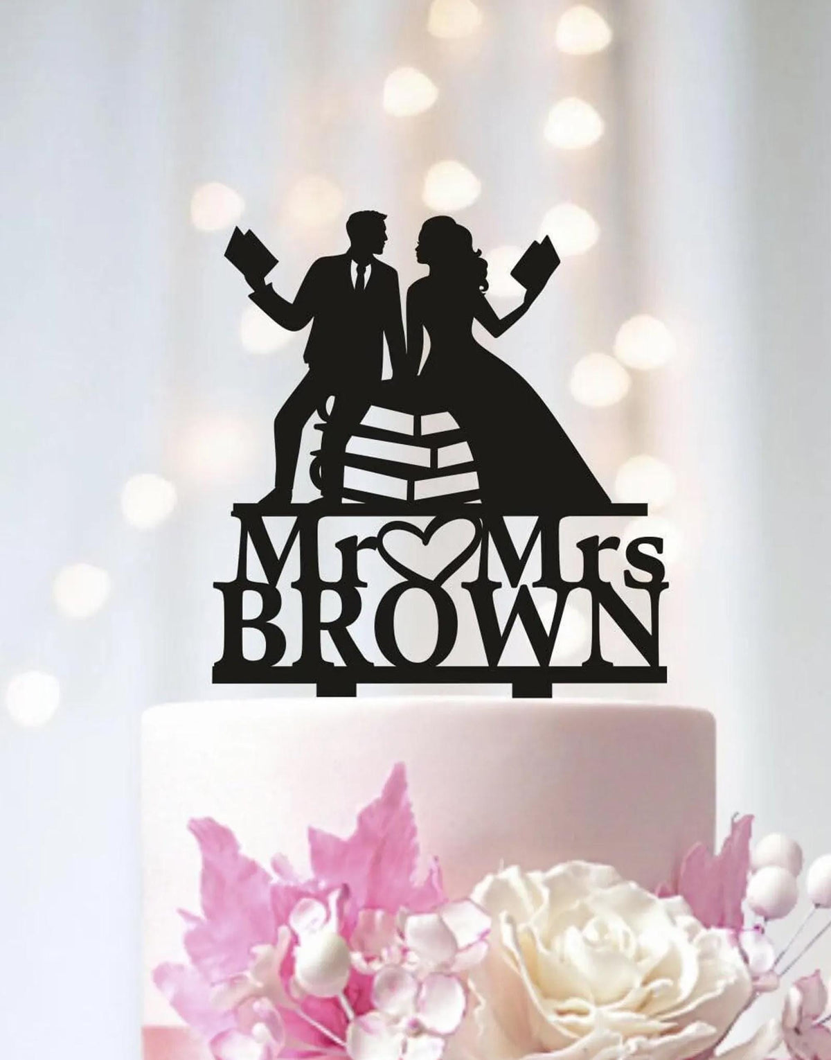 A black silhouette of a man and a woman holding books, with the text "Mr. Brown" below them, on a white cake.