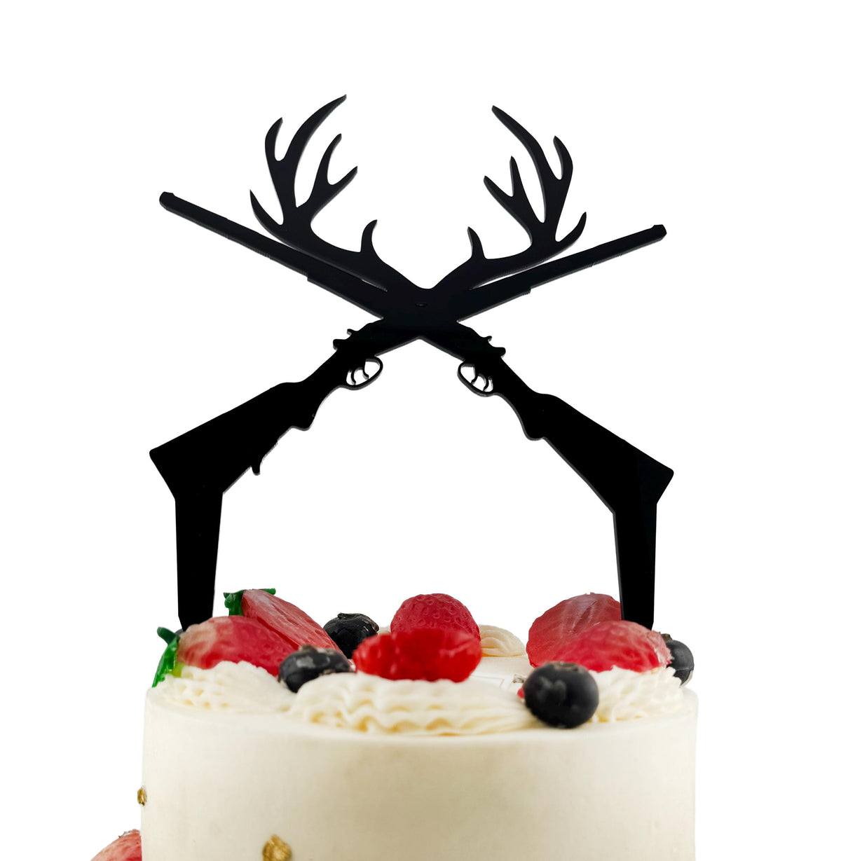 A white cake with a black silhouette of a gun crossed over it, topped with berries and whipped cream.
