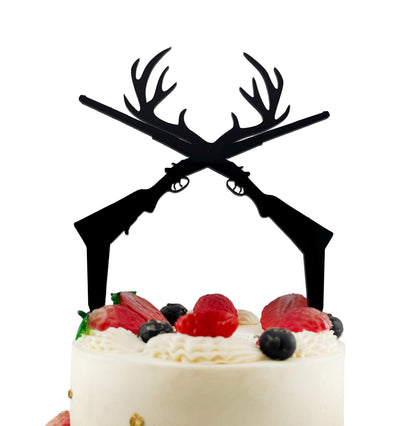 A white cake with a black silhouette of a gun crossed over it, topped with berries and whipped cream.