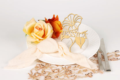 a white plate with a decorative centerpiece, including a wooden name card, roses, and a beaded tablecloth.