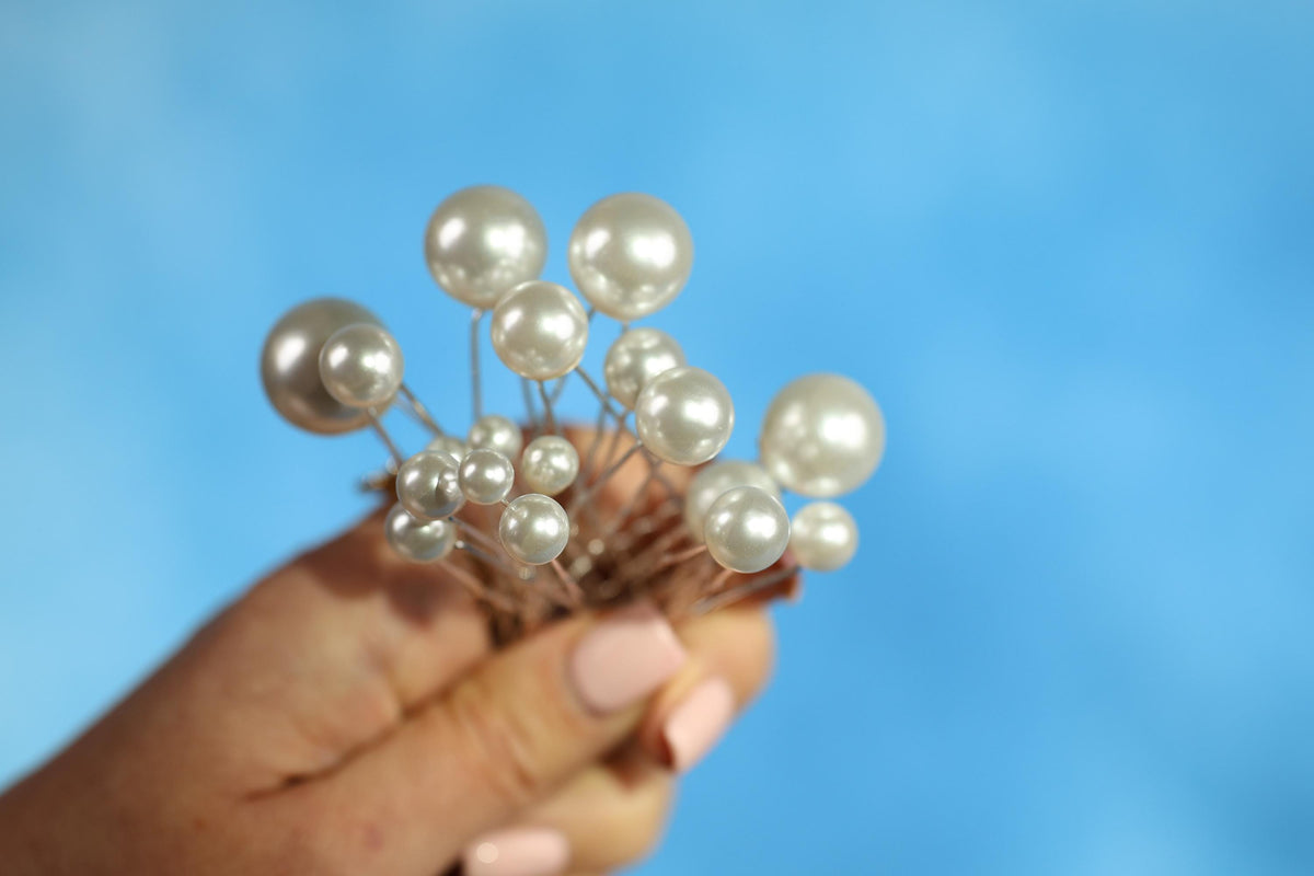 A hand holding a cluster of small, white pearls against a blue background.