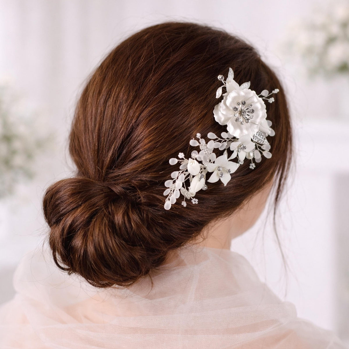 a woman's back view with her hair styled in a bun, adorned with a decorative flower accessory.