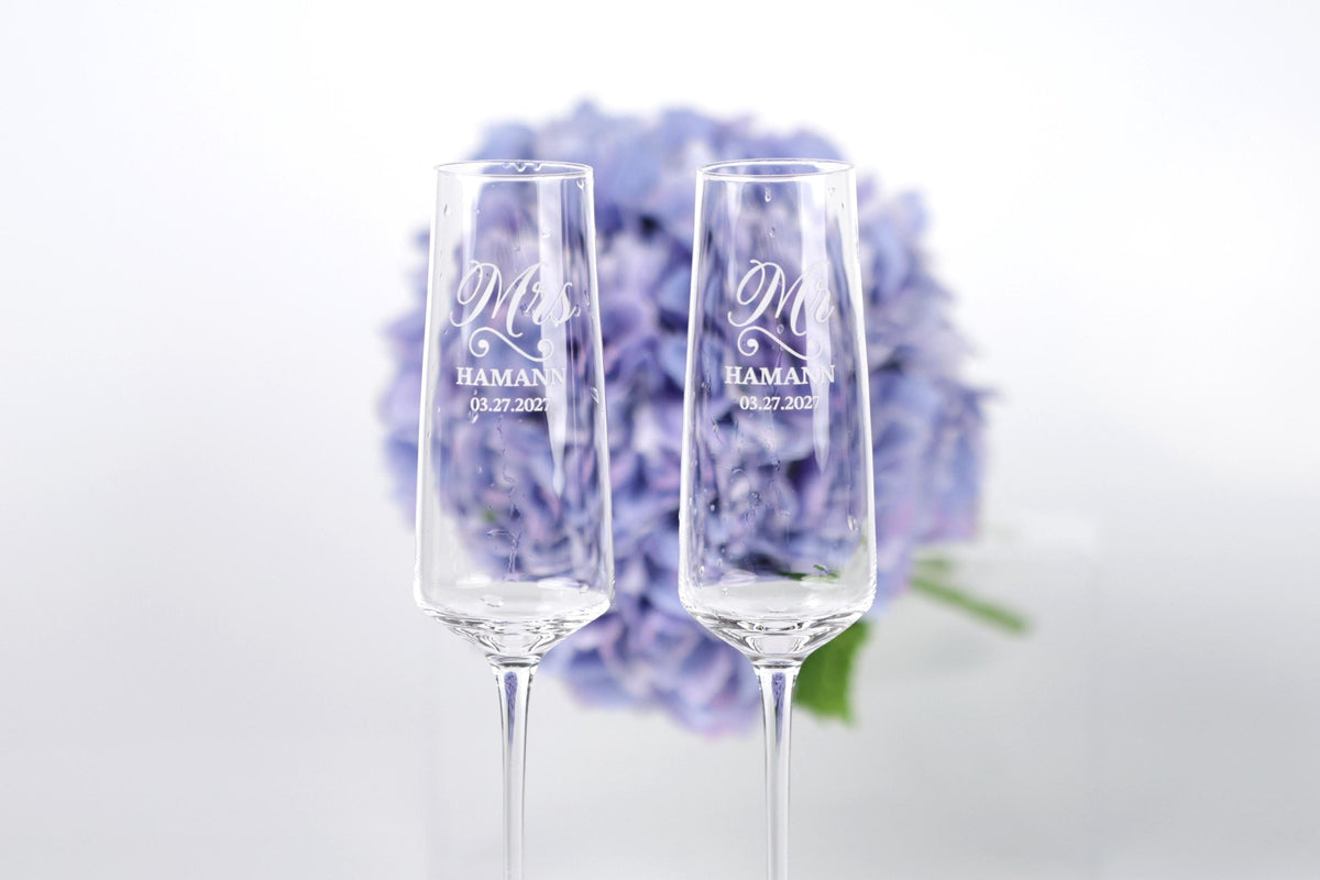 two champagne flutes with personalized messages, placed in front of a background of purple flowers.