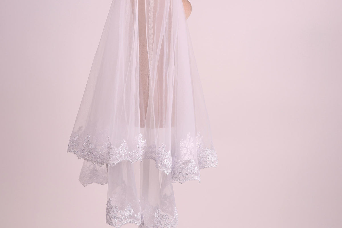 A white veil with lace trim is shown against a pink background.