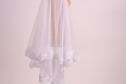 A white veil with lace trim is shown against a pink background.