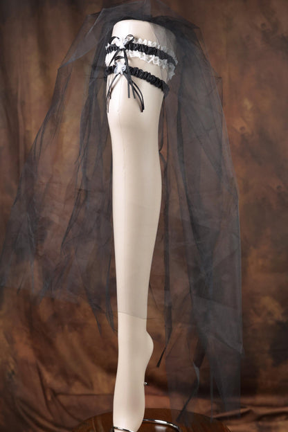 A mannequin leg wearing a black and white lace garter belt and a black veil.