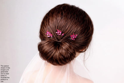 a woman's hair styled in a bun, with three small, pink flower-shaped hair clips attached to the hair.