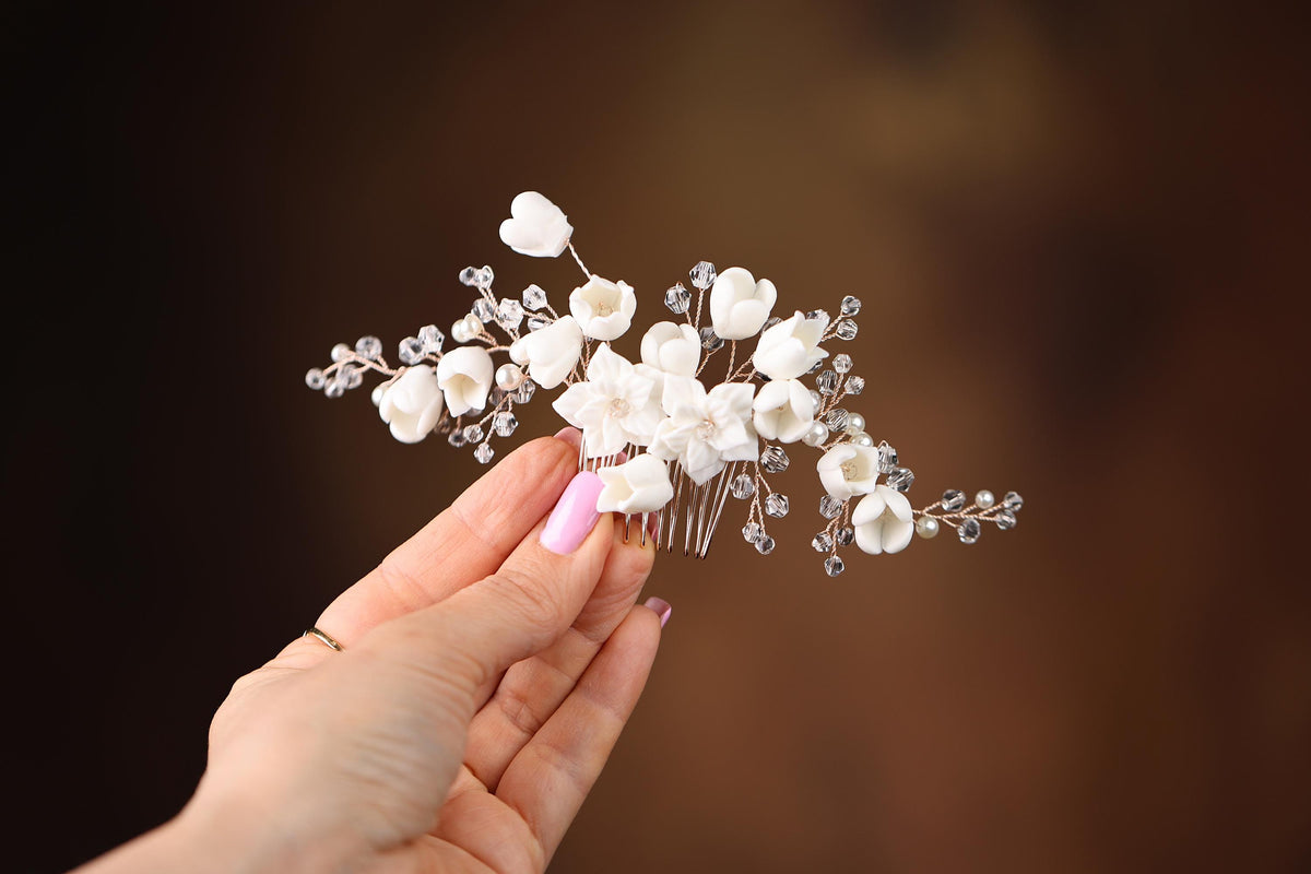 a hand holding a white flower and a hair comb