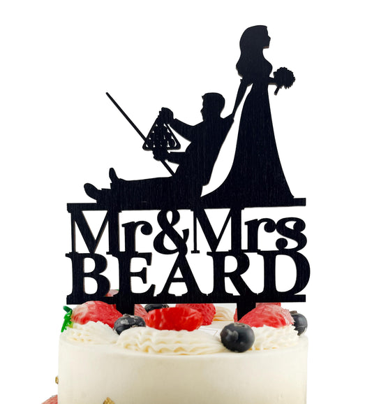 A silhouette of a bride and groom on a cake topper, with the text "Mr & Mrs BEARD" below.