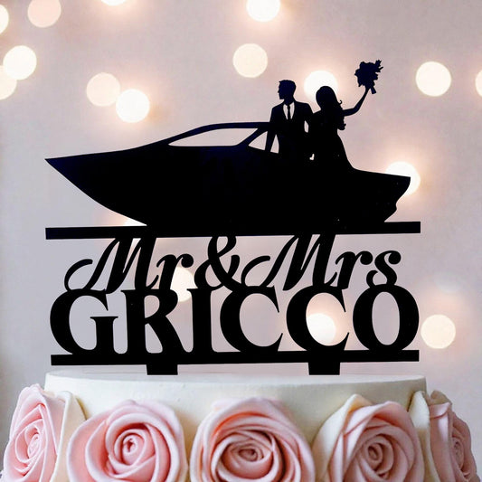 A silhouette of a couple on a boat, with the text "Mr & Mrs GRICCO" on a cake topper.