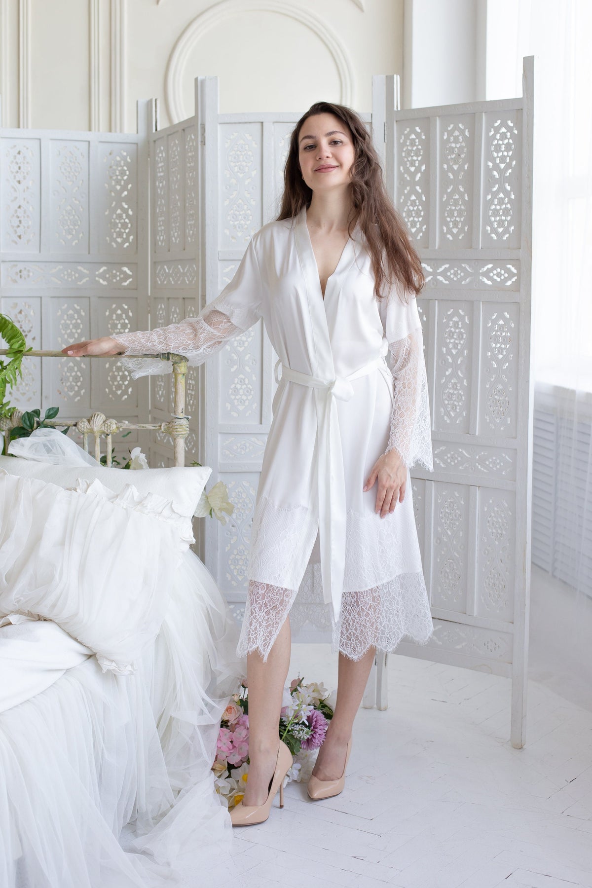 a woman standing next to a bed in a white room