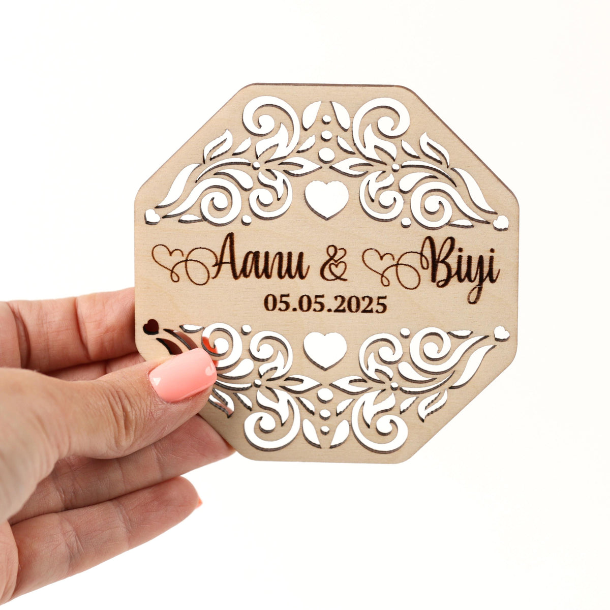 A hand holding a wooden card with a floral design and text on it.