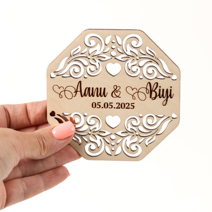 A hand holding a wooden card with a floral design and text on it.