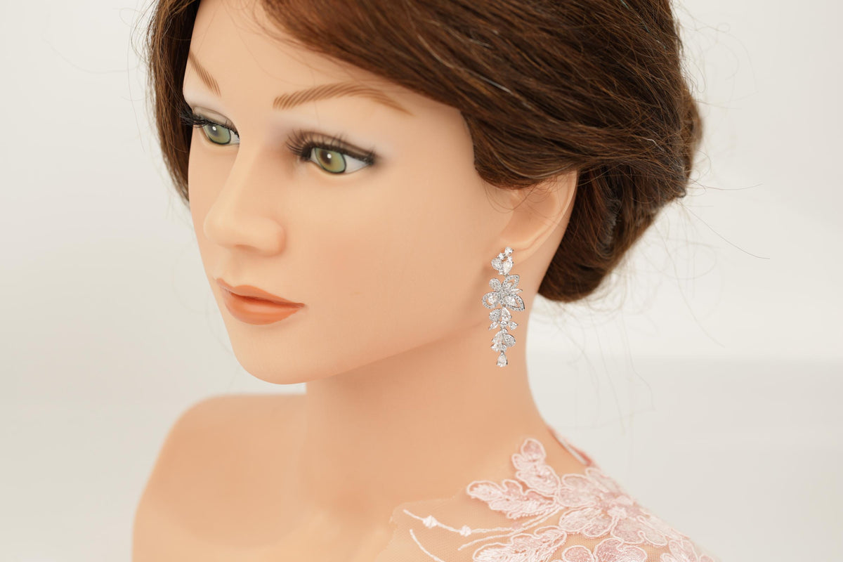 A close-up of a mannequin head wearing a pair of earrings with a floral design.