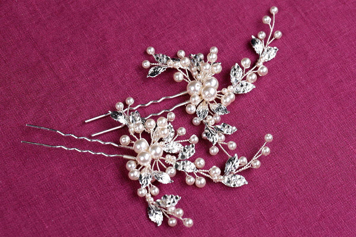 a pair of hair pins with pearls and leaves