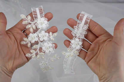 a pair of hands holding a pair of wedding garters