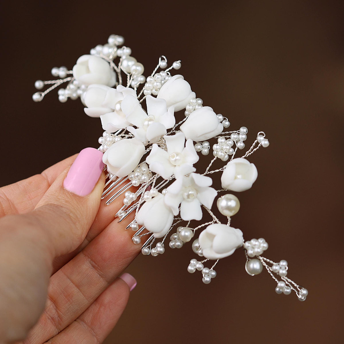 a hand holding a white flower and pearl hair comb