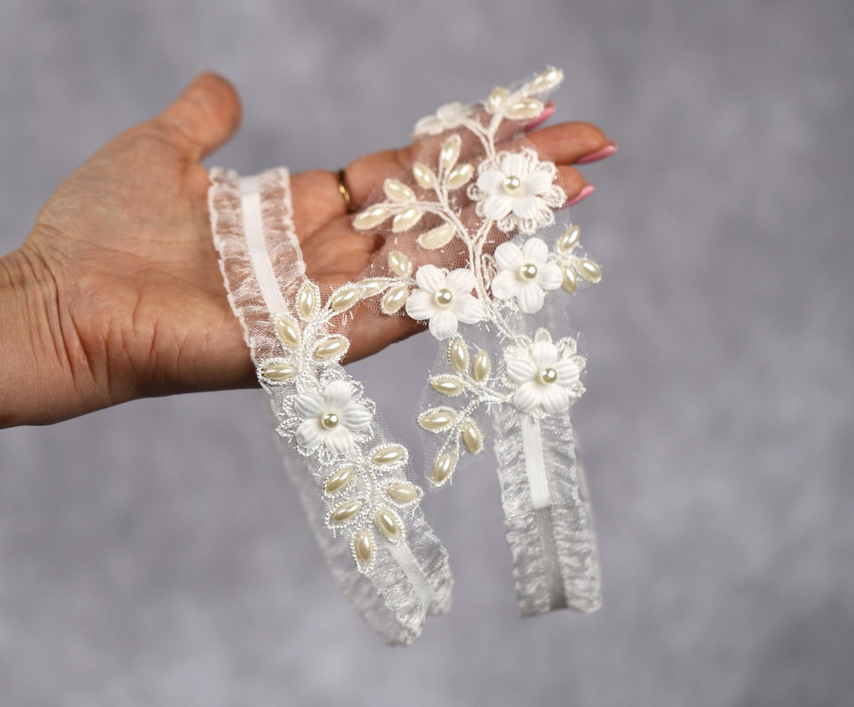a hand holding a pair of wedding garters