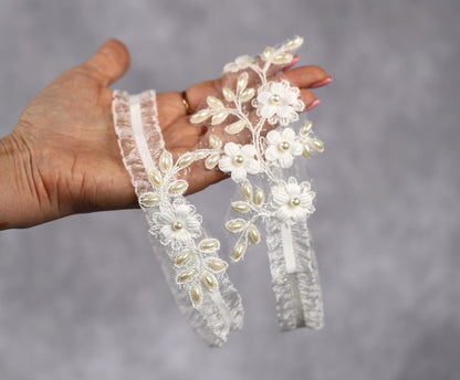 a hand holding a pair of wedding garters