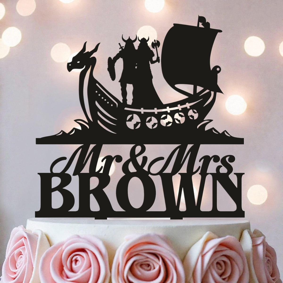A black silhouette of a couple on a boat with a dragon, along with the text "Mr & Mrs BROWN" on a cake.