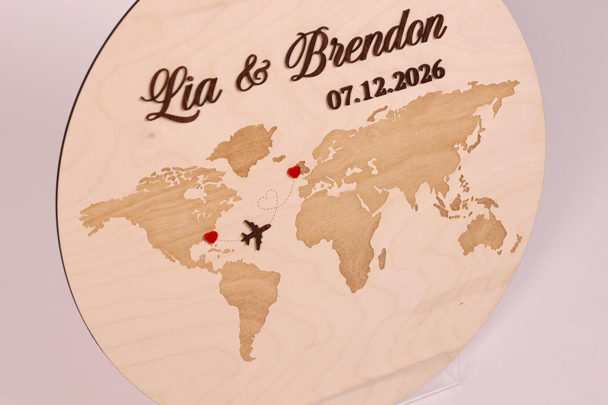 A wooden sign with a world map and two heart-shaped symbols, one in each continent, indicating the names of the couple.