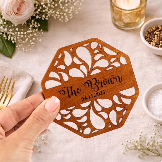 A hand holding a wooden coaster with the text "The Brown" and the date "04.11.2025" printed on it.