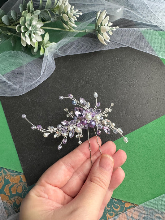a person is holding a flower brooch in their hand