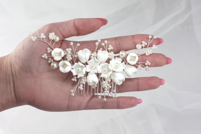 a woman's hand holding a white flower and pearl hair comb