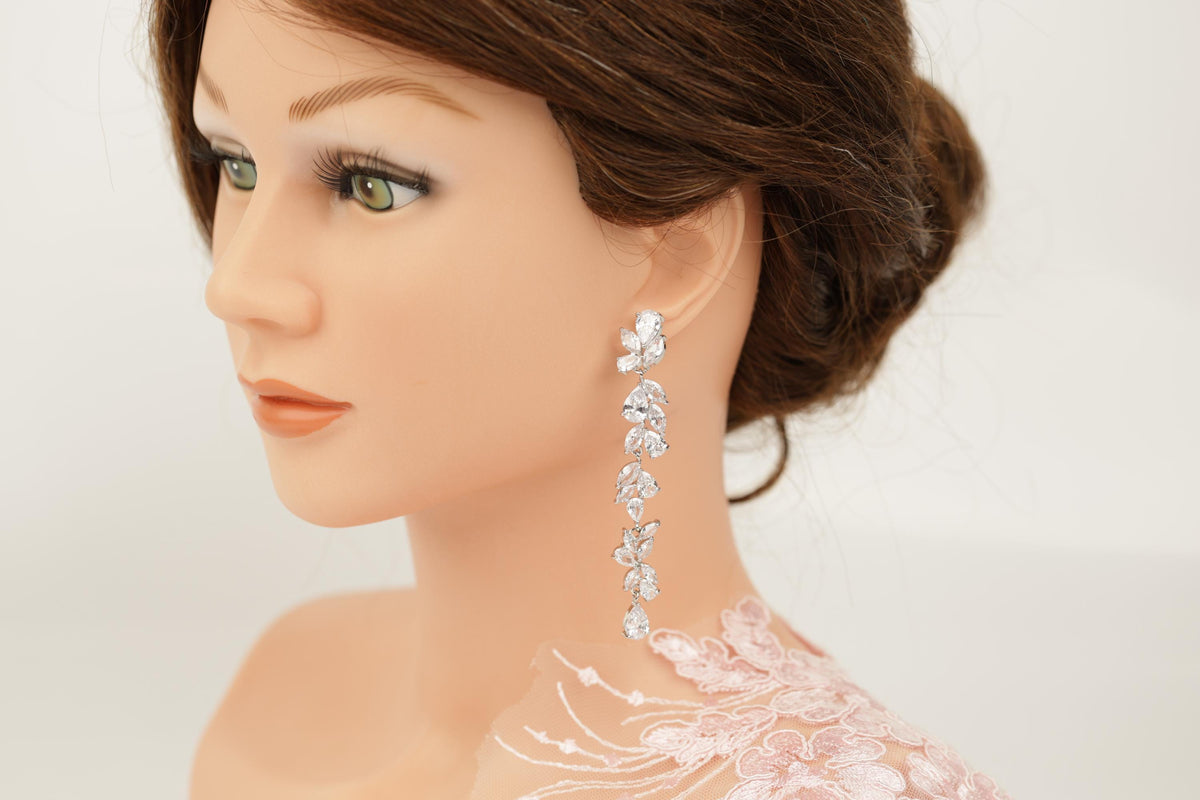 A close-up of a woman's face wearing a pair of dangling earrings with a floral design.