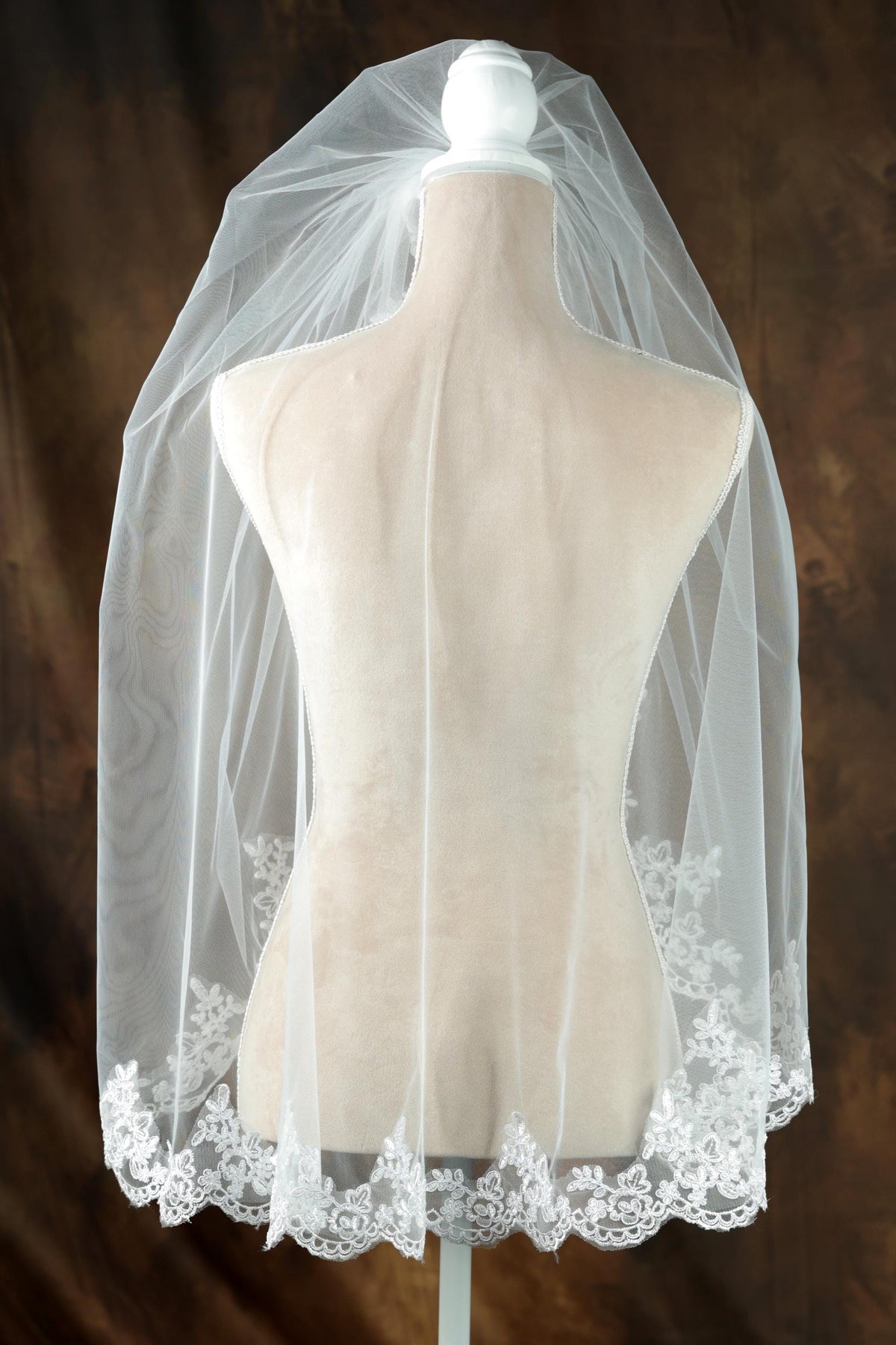 A mannequin wearing a white wedding veil with a delicate lace trim.