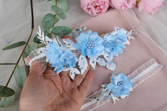 a hand is holding three blue flowers on a piece of cloth
