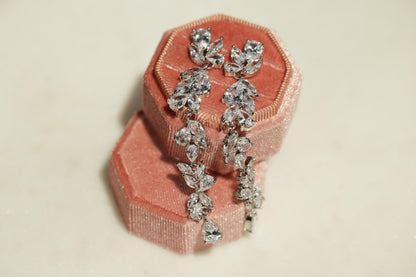 A pair of elegant earrings with sparkling crystal stones, displayed in a pink velvet box.