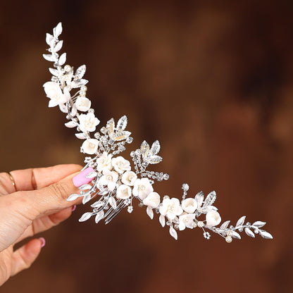 a woman holding a white flower and leaf tiara