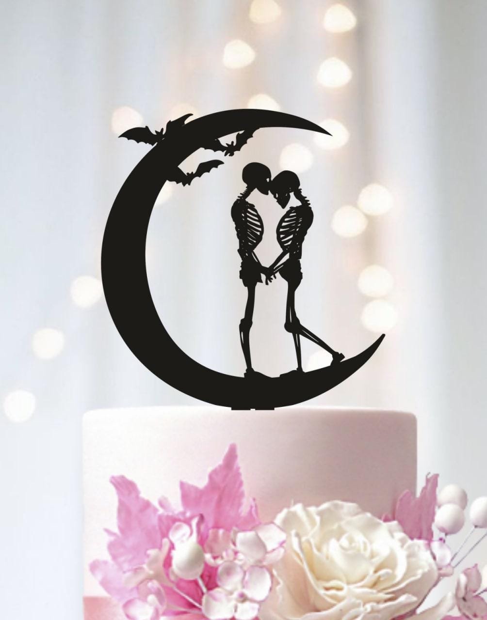 A black silhouette of a skeleton couple embracing on a crescent moon, with bats flying above them, is the central focus of the image.
