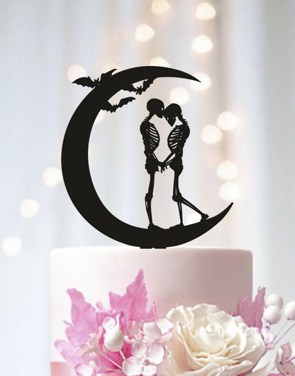 A black silhouette of a skeleton couple embracing on a crescent moon, with bats flying above them, is the central focus of the image.