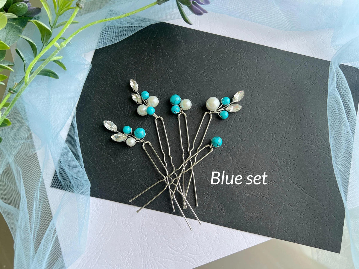 A collection of silver hair clips adorned with turquoise and white stones, arranged on a black surface.