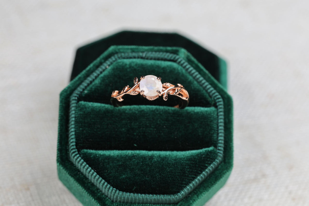 a green velvet ring box with a ring in it