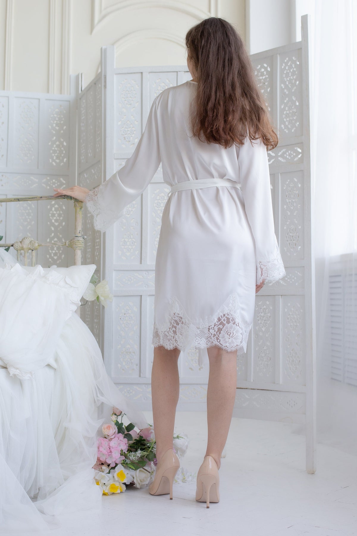 a woman in a white robe standing next to a bed