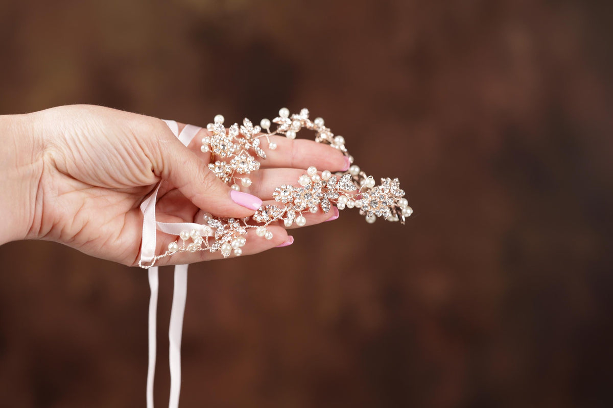 a woman's hand holding a tiara with pearls