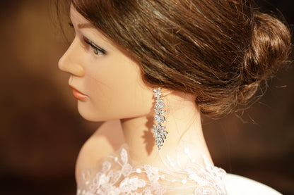 A close-up of a woman's face wearing a diamond earring, with her hair styled in a bun.