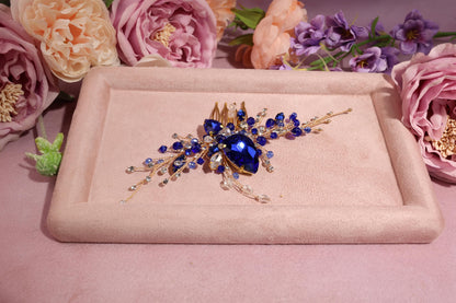 a blue brooch sitting on top of a pink tray