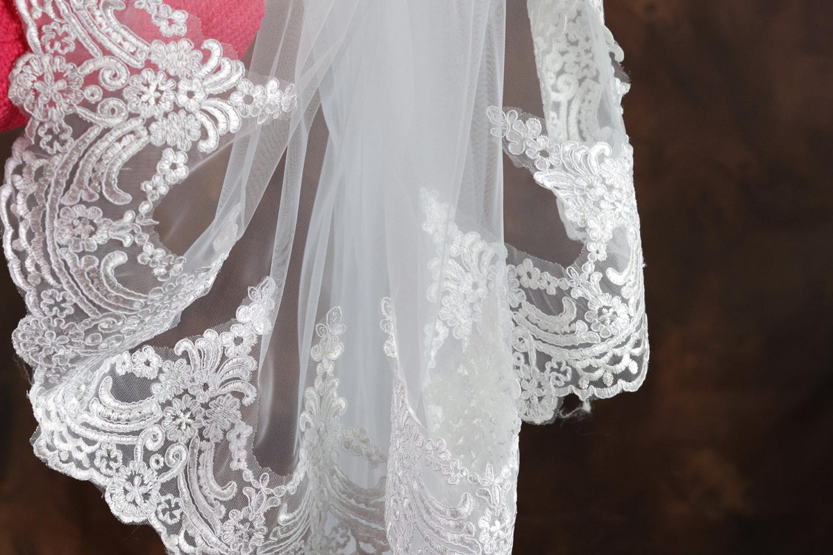 A close-up view of a delicate white lace veil with intricate floral embroidery.