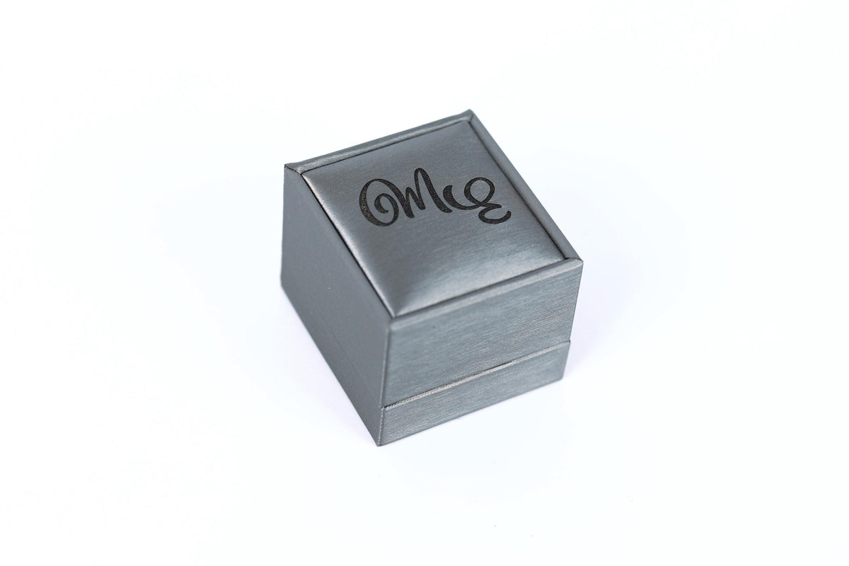 A small, square-shaped metal box with the word "Mee" engraved on it.