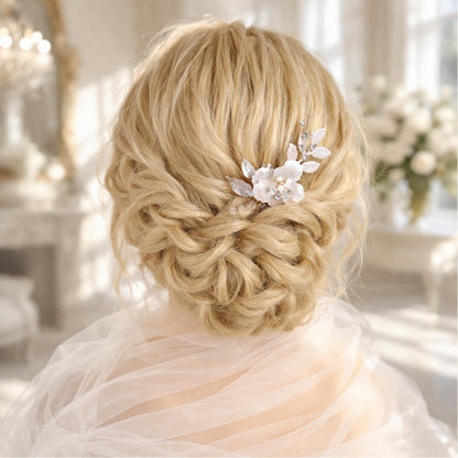 a woman's blonde hair styled in an elegant updo, adorned with a delicate flower accessory.