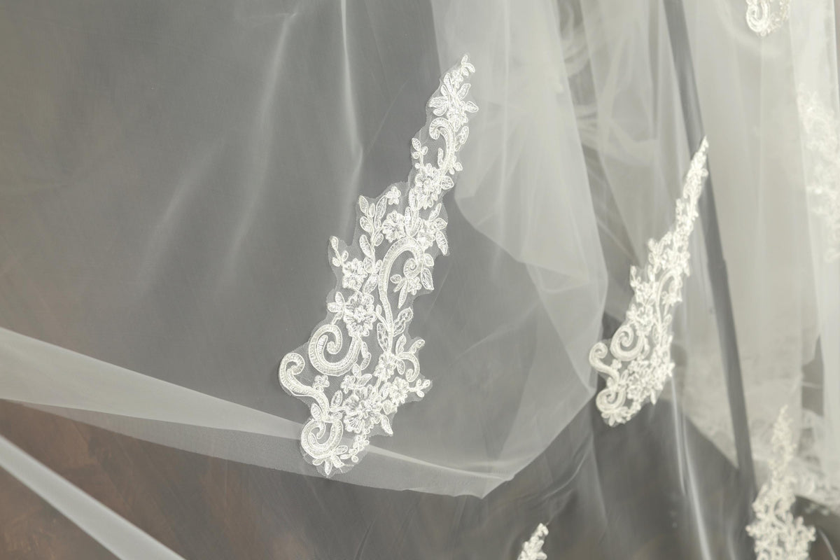 a close-up view of a delicate white lace veil with intricate floral embroidery.