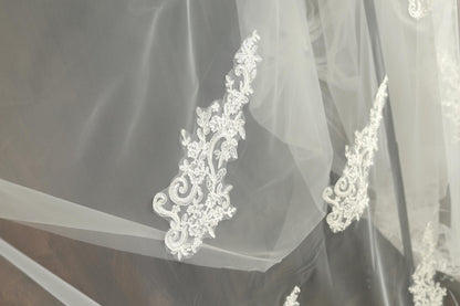 a close-up view of a delicate white lace veil with intricate floral embroidery.