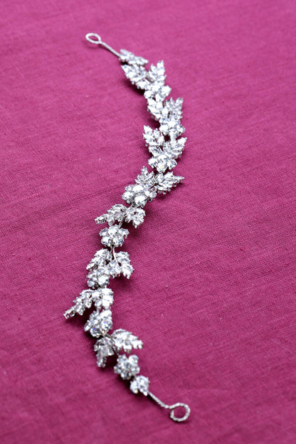 a close up of a piece of jewelry on a pink surface